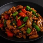 Stir-fried chicken with bell peppers, peanuts, and chili peppers coated in a glossy Kung Pao sauce.