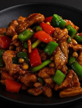 Stir-fried chicken with bell peppers, peanuts, and chili peppers coated in a glossy Kung Pao sauce.