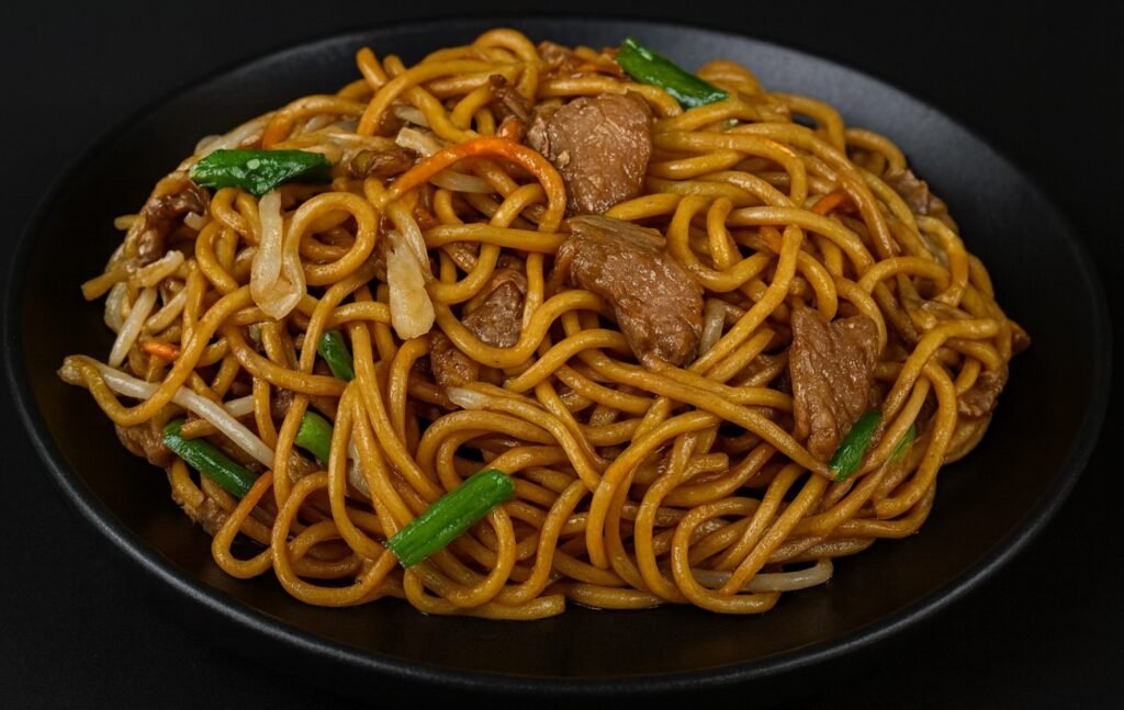 A bowl of lo mein noodles stir-fried with bell peppers, cabbage, carrots, and green onions.
